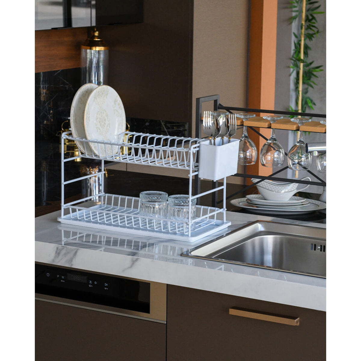 White two-tier dish rack holding plates beside a kitchen sink