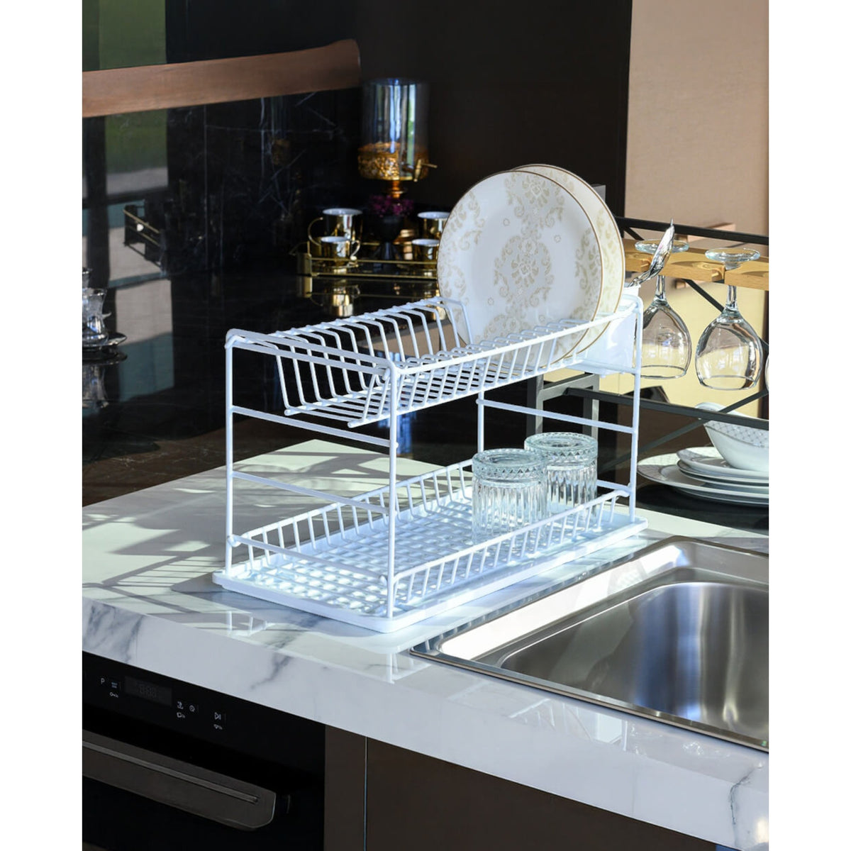 White two-tier dish drainer beside a stainless steel kitchen sink