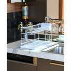 White two-tier dish drainer with plates on a kitchen worktop