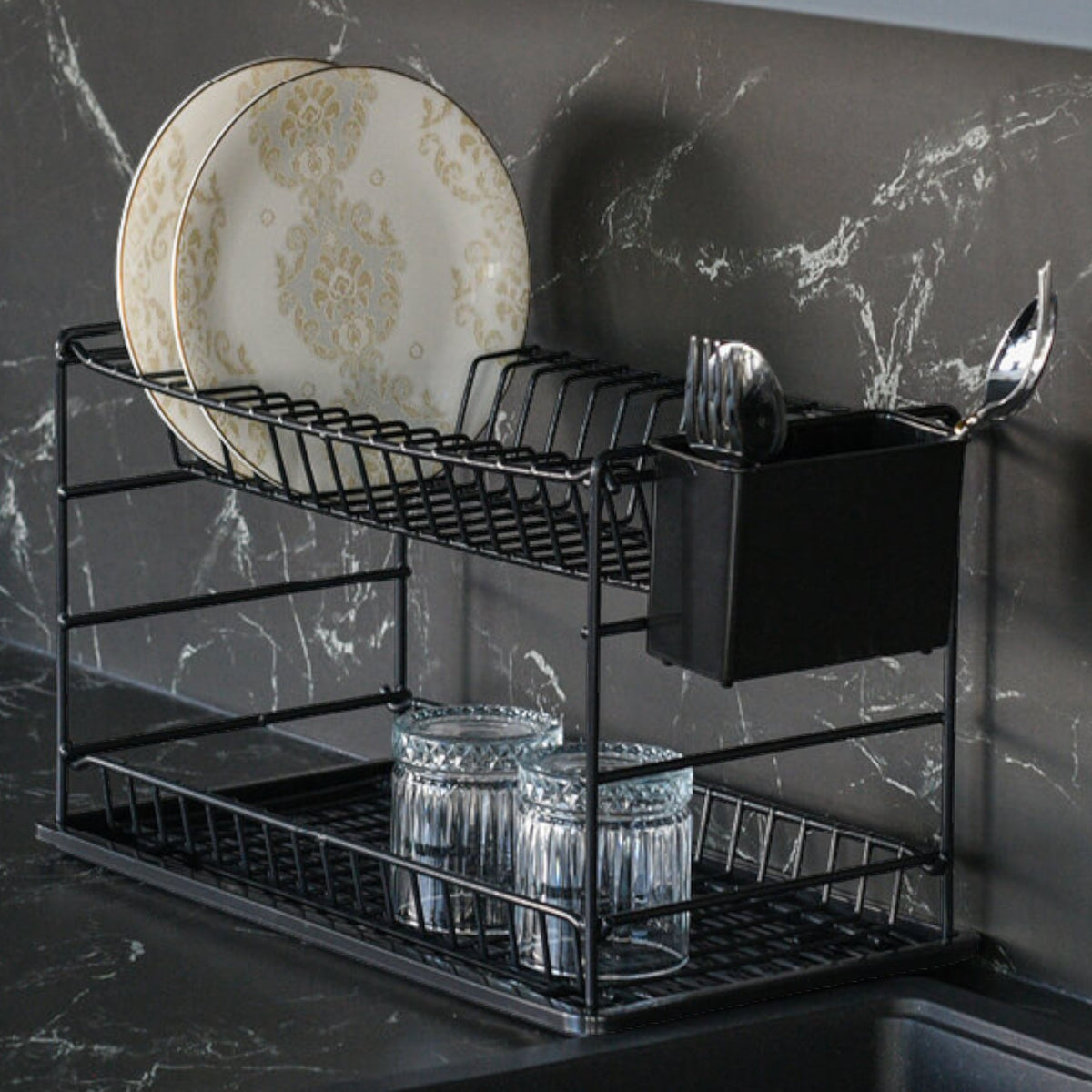 Close-up of a black two-tier dish rack holding plates, glasses and cutlery