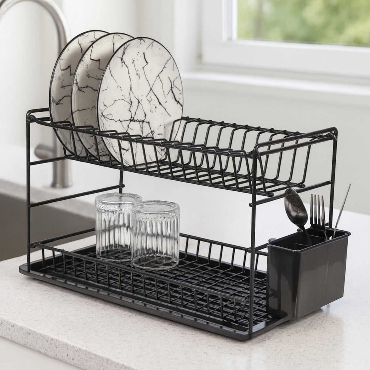Black two-tier dish rack holding plates and glasses on a kitchen worktop