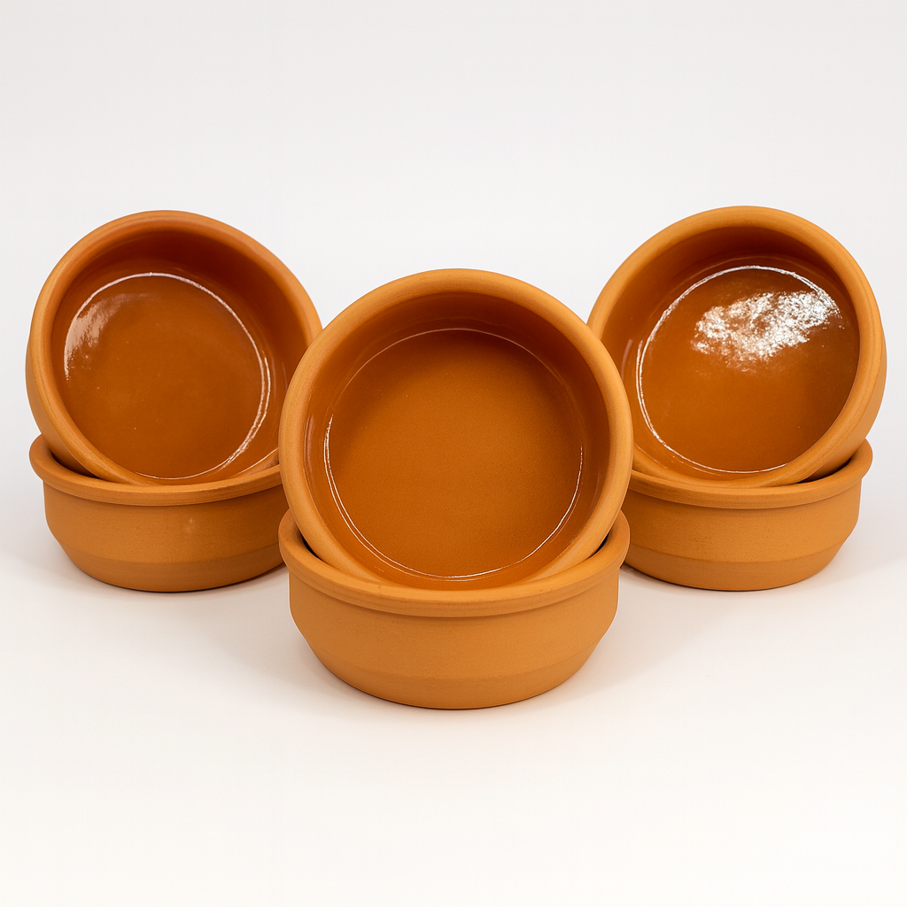 Six terracotta tapas dishes stacked in pairs with upright dishes showing the glaze