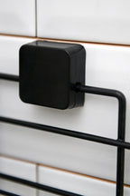 TheOwnas black adhesive mount for a rectangular shower caddy attached to white tiled wall